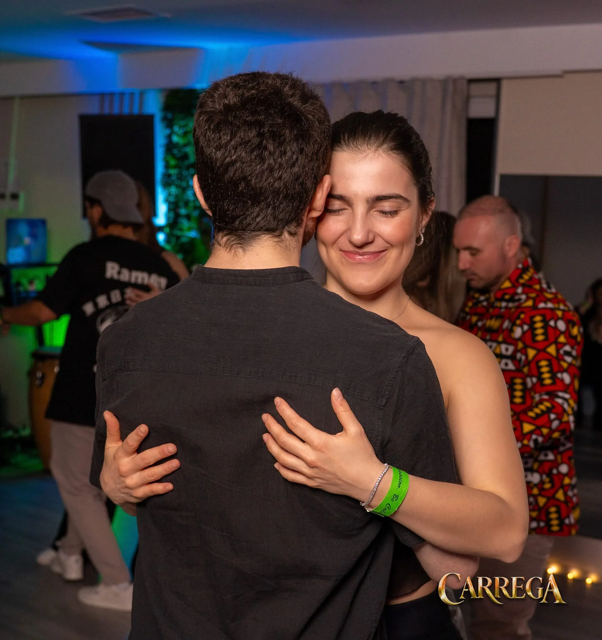Doi oameni dansează kizomba aproape, femeia zâmbind cu ochii închiși
