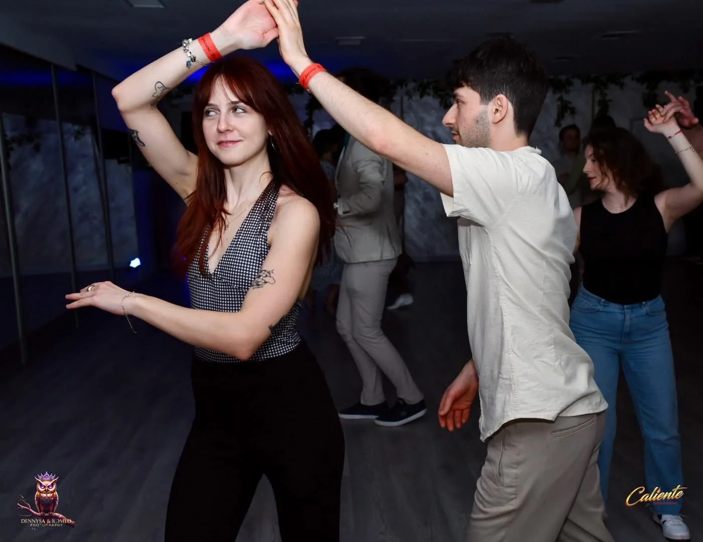 Ilustrație: O sală de dans modernă, cu siluete de dansatori în mișcare și logo-ul Caliente Dance Studio, simbolizând un mediu primitor pentru învățarea Salsa On2.